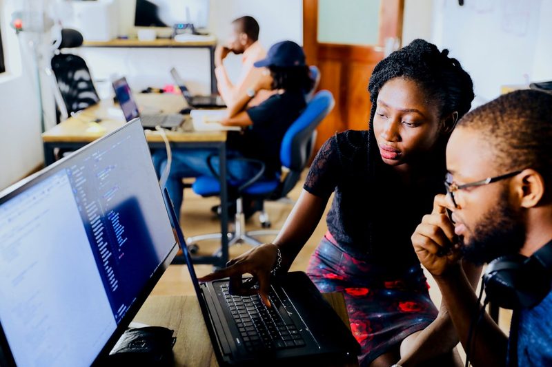 Two developers reviewing code together on a laptop in an office